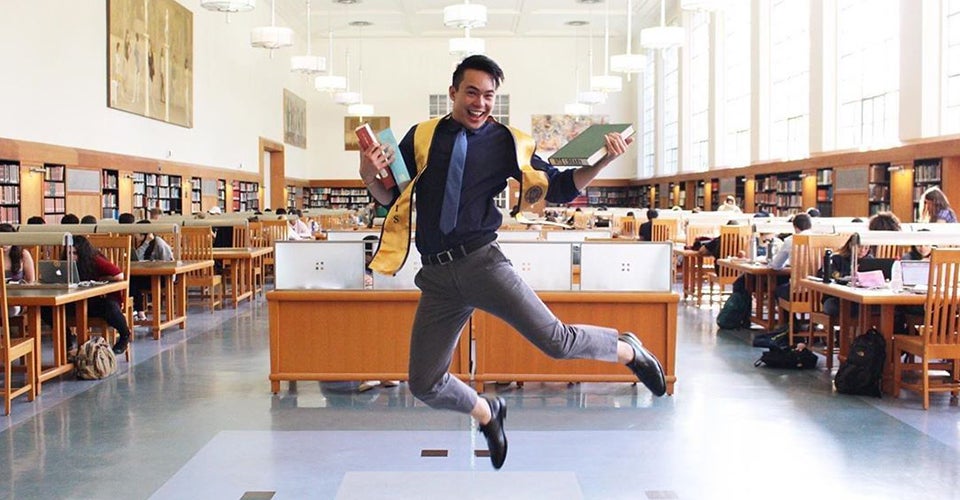 student poses with books in uc davis shields library