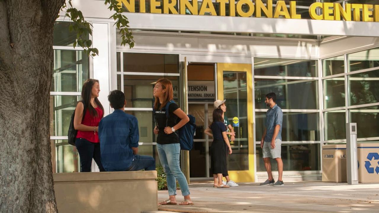 A small group of students talking outside the International Center  -  International Admission