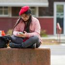 A student wearing a beret uses their smartphone outside of the 澳门六合彩开奖结果走势图 Craft Center.
