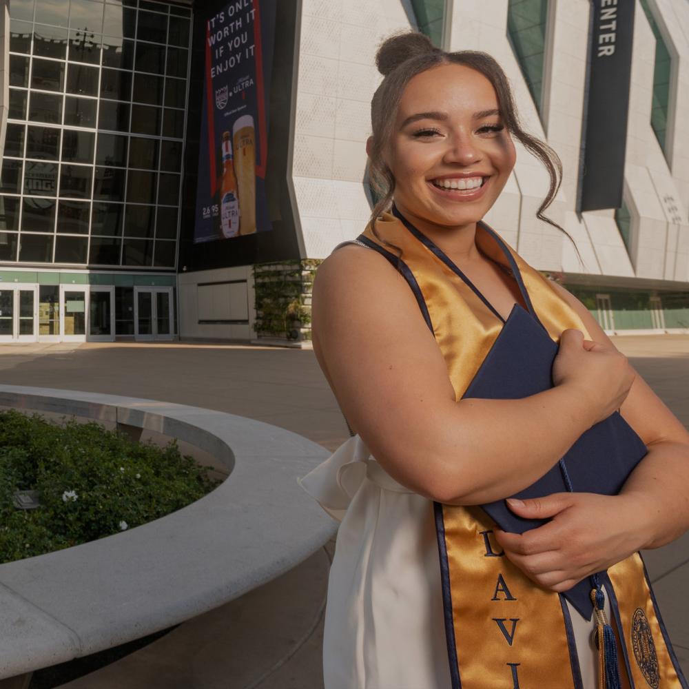 A 澳门六合彩开奖结果走势图 student standing outside of the Golden 1 center holdint their grad regalia